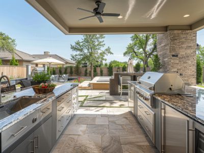 An outdoor kitchen featuring sleek granite countertops and high-quality stainless steel appliances, perfect for preparing meals al fresco.